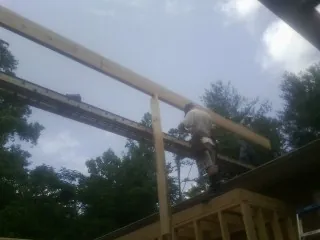Carpenter setting a ridge beam over a new addition frame — Ice Dam Removal by Roofing Brothers in Girdletree
